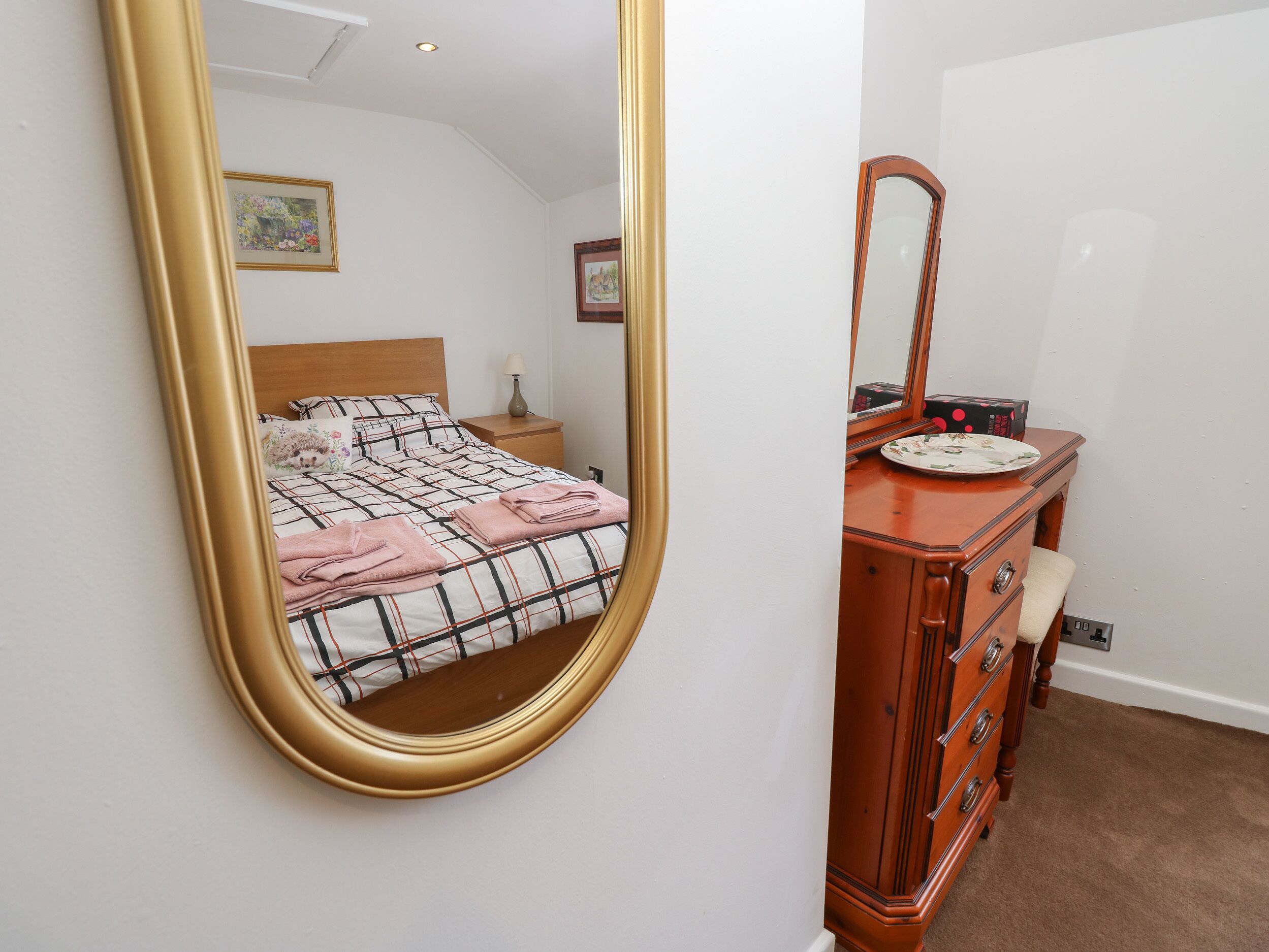 Un dormitorio con cama, cómoda, espejo y mesita de noche.