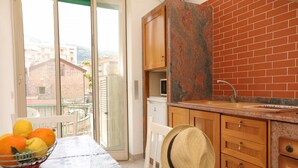 A kitchen with a brick wall, wooden cabinets, a sink, and a table with a fruit bowl. - Suite Pina Ocean in Sorrento (Sorrento)
