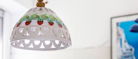 Eine Pendelleuchte mit weißem, gewelltem Design und grünen Blättern mit roten Beeren.