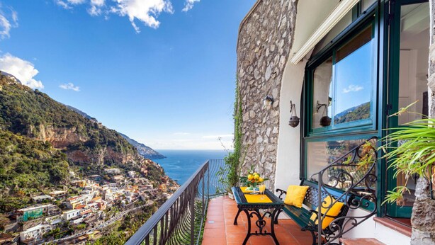 A balcony with a table and chairs, overlooking a coastal village and the sea. - Relaxing Positano in Positano (Positano)