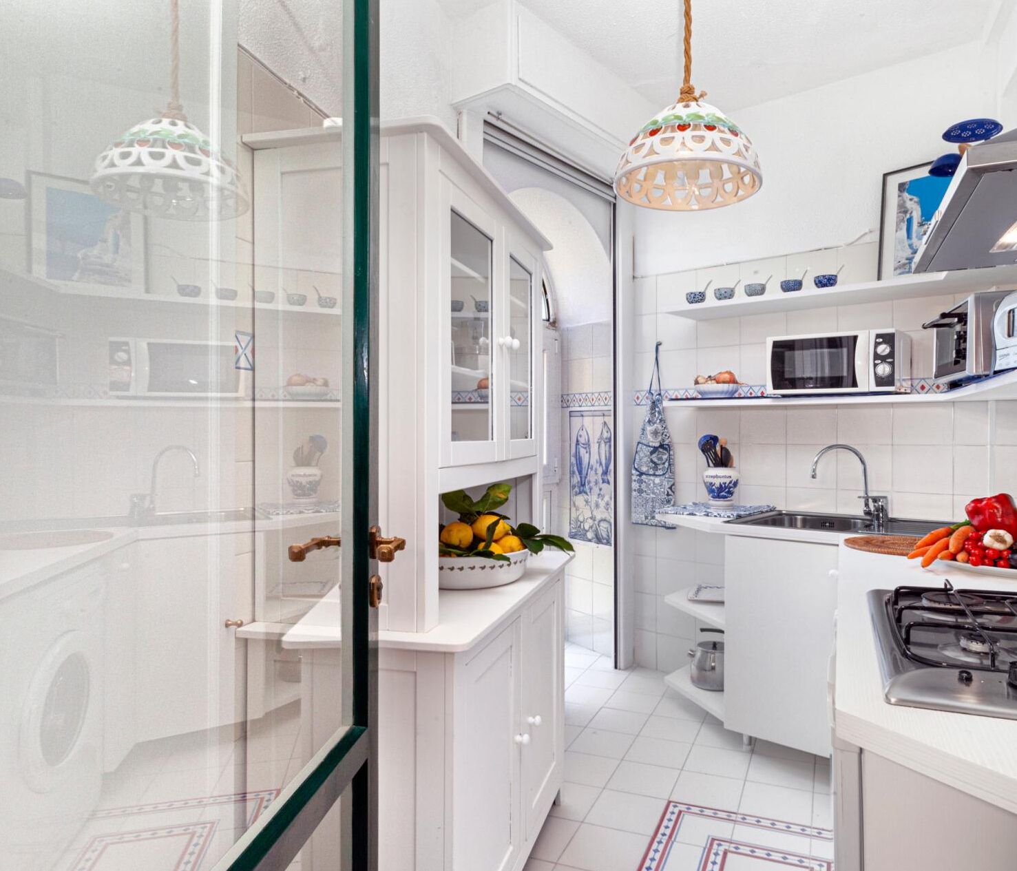 Une cuisine de taille réduite avec des meubles blancs, un four à micro-ondes, un évier et une cuisinière.