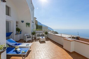 Un balcone luminoso con terrazza, pareti bianche e vista sul mare.