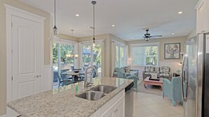 A kitchen with granite countertops, a stainless steel sink, and a ceiling fan. - Oasis by the Beach managed by the Beach Retreats (Holmes Beach)