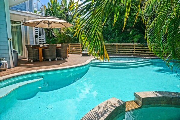 A swimming pool with a wooden deck, outdoor furniture, and a pergola with an umbrella. - Oasis by the Beach managed by the Beach Retreats (Holmes Beach)