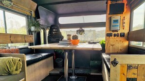 Een ruimtelijk keukenhoekje met een tafel, zitplaatsen en een raam met uitzicht.