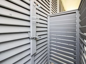 A metal gate with a white metal shelf attached to a building's exterior wall. - Adventure Awaits by Ryson Vacation Rentals (Galveston)