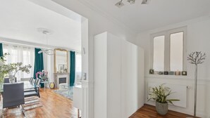 Tilava huone, jossa on puulattia, lasipöydällä ja -tuoleilla varustettu ruokailutila, takka ja suuri peili seinällä.