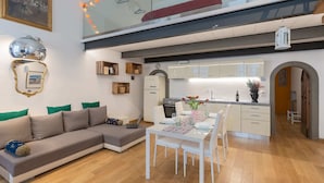 A modern living room with a sectional sofa, a dining table, and a kitchen in the background. - Monalda Loft 2 (Florence)