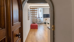 A hallway with a wooden door, a red bench, and a staircase leading to another room. - Monalda Loft 2 (Florence)