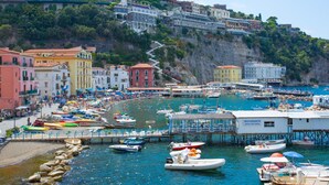 A coastal town with colorful buildings, a marina with boats, and a hillside with residential structures. - Casa Annal in Sorrento (Sorrento)