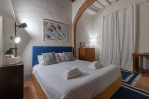 Cama bem arrumada com colcha listrada, cabeceira e obra de arte na parede.