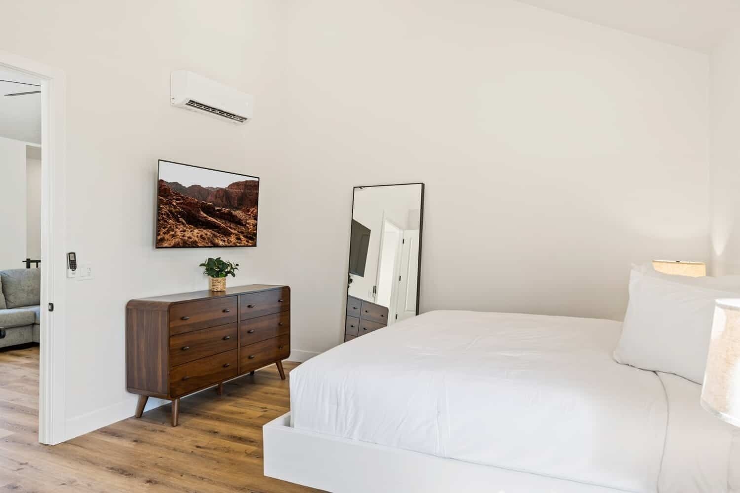 Un dormitorio con cama, cómoda, espejo y aire acondicionado instalado en la pared.