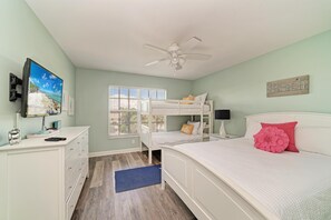 A bedroom with bunk beds, a desk with a computer, a TV, and a ceiling fan. - Kickback Cabana managed by Beach Retreats (Holmes Beach)