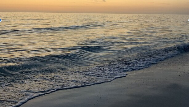 A beach with calm waves and a clear sky.