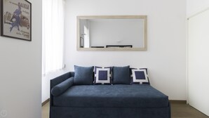 A modern living room with a dark blue sofa, two decorative pillows, and a large mirror on the wall. - Italianway - Mauro Macchi 65 (Milan)