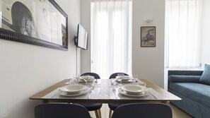 Enjoy meals in this stylish dining area with a table for two, a sofa, and a large framed picture above.