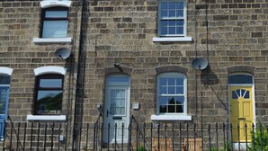 Un edificio de piedra con varias ventanas, una puerta amarilla y una cerca de metal negro.
