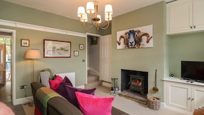 Una sala de estar con sofá, cojines coloridos, chimenea, televisor y candelabro.