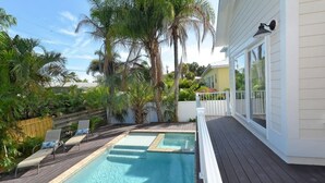 Ein Poolbereich mit zwei separaten Abschnitten, umgeben von Palmen und einer Holzterrasse.