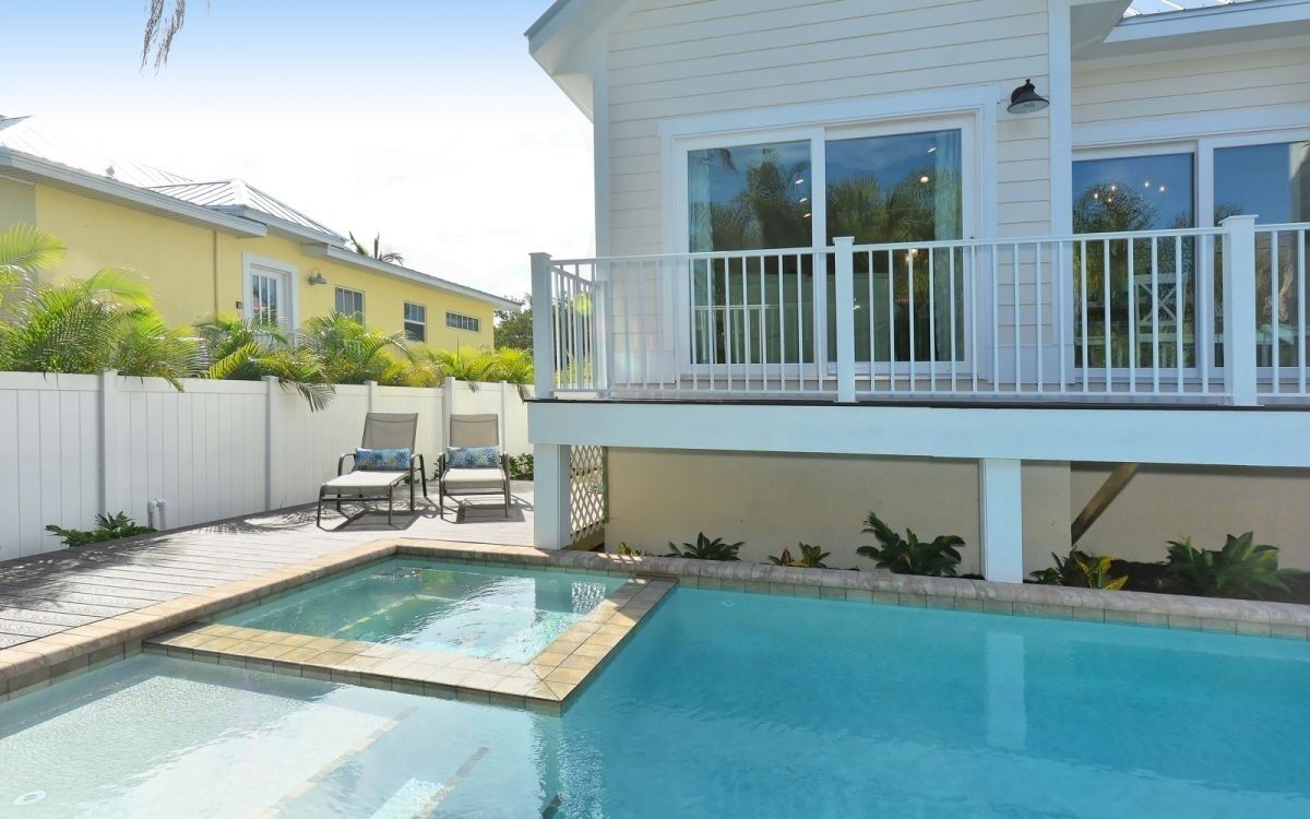 A residential property with a swimming pool, a covered deck, and a white fence.