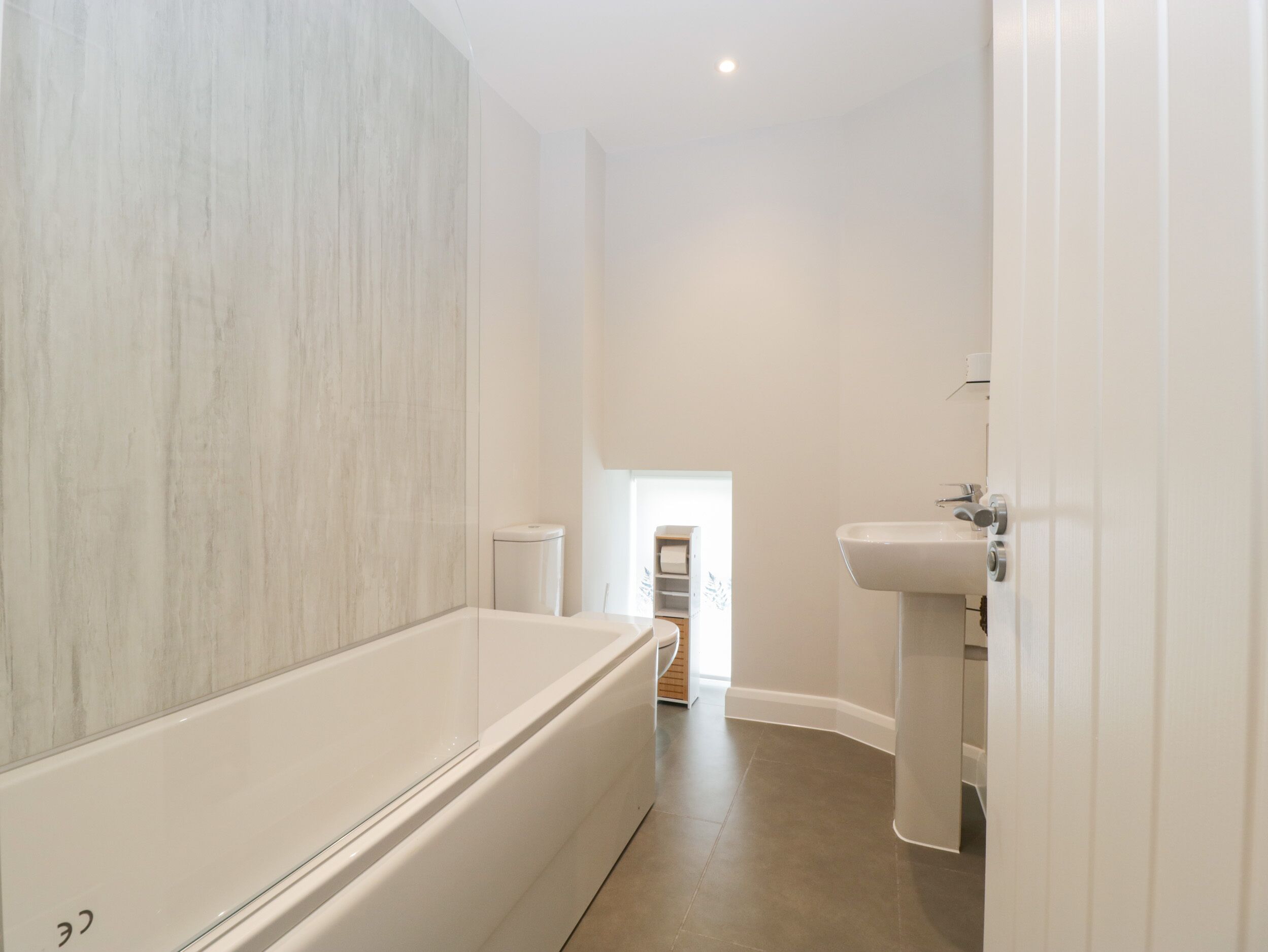 A modern bathroom with a large bathtub, a sink, and a toilet.