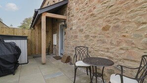 A stone building with a wooden deck, outdoor seating, and a covered area. - The Old School (Ross-on-Wye)