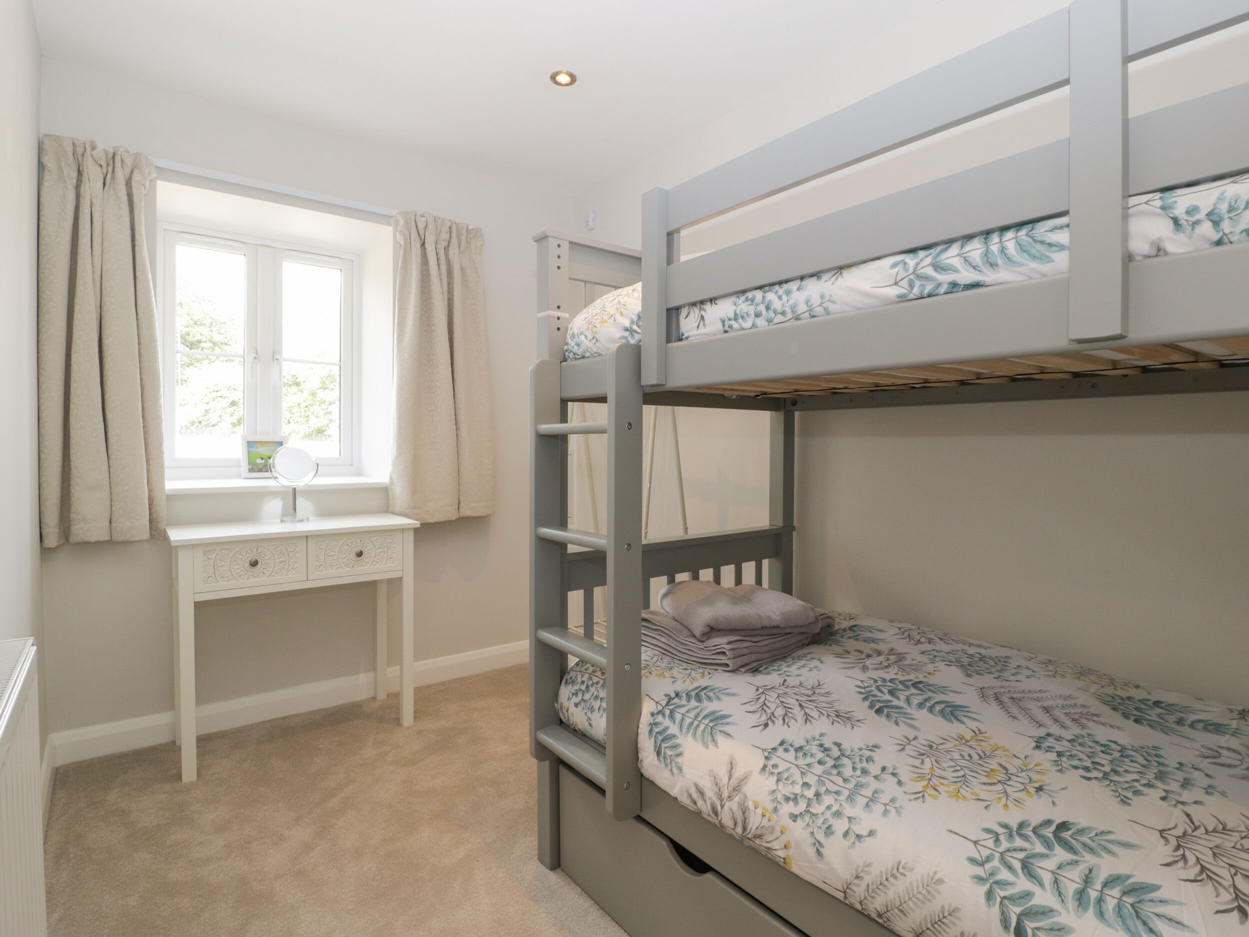 A bunk bed room with a desk and window.