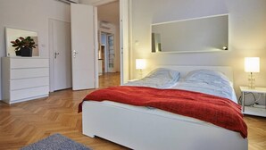 A bedroom with a bed, bedside lamps, a dresser, and a mirror.