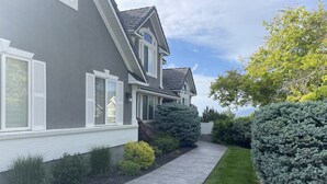 A modern two-story house with a grey exterior and white trim, a concrete pathway, and well-maintained green lawns and shrubs. - Sunset Views! Indoor Sport Court, Pool table, Golf Course, 12 min to downtown  (North Salt Lake)