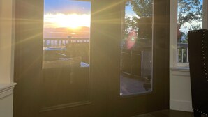 A room with a dark wooden door, a window with a view of the sunset, and a chair near the window. - Sunset Views! Indoor Sport Court, Pool table, Golf Course, 12 min to downtown  (North Salt Lake)