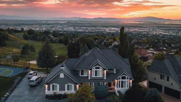 A residential house with a driveway, a lawn, and a view of a cityscape and mountains in the background. - Sunset Views! Indoor Sport Court, Pool table, Golf Course, 12 min to downtown  (North Salt Lake)