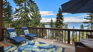A deck with two lounge chairs, a table, and a large umbrella. - Eagles Perch Cabin - Pano Lake Views, Fido Friendly (Carnelian Bay)
