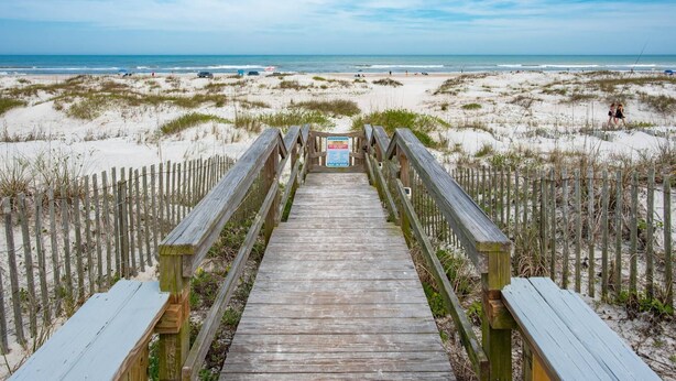 A wooden boardwalk leading to a beach with a clear view of the ocean. - The Sand Castle (St. Augustine)