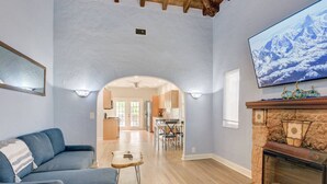 Un salon doté d’une cheminée, d’un téléviseur fixé au mur et d’un coin repas visible à travers une arche.