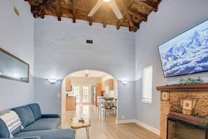 Un soggiorno con camino, una TV a parete e una sala da pranzo visibile attraverso un arco.