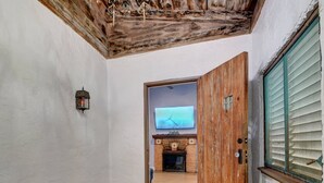 Un couloir avec une porte en bois, un téléviseur fixé au mur et une cheminée en pierre.
