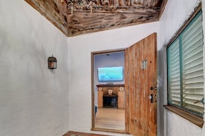Un corridoio con una porta in legno, un televisore fissato alla parete e un camino in pietra.