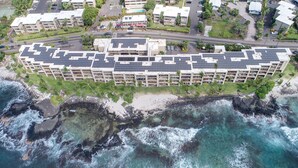 An aerial view of a hotel with multiple floors, solar panels on the roof, and a beachfront location.