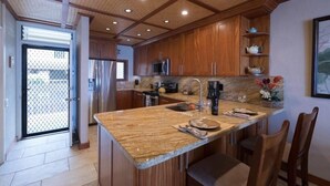 A kitchen with wooden cabinets, granite countertops, stainless steel appliances, and a large island.