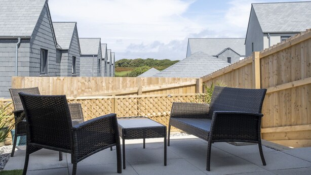 Eine Terrasse mit Korbmöbeln und einem Holzzaun.