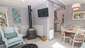 A cozy living room with a fireplace, a dining area, and a kitchen in the background.