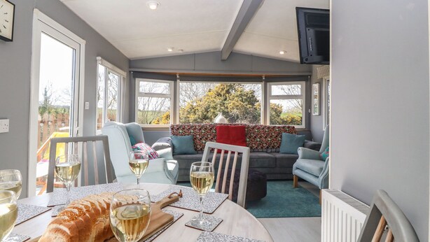 A modern living room with a dining area, large windows, and a view of the outdoors.