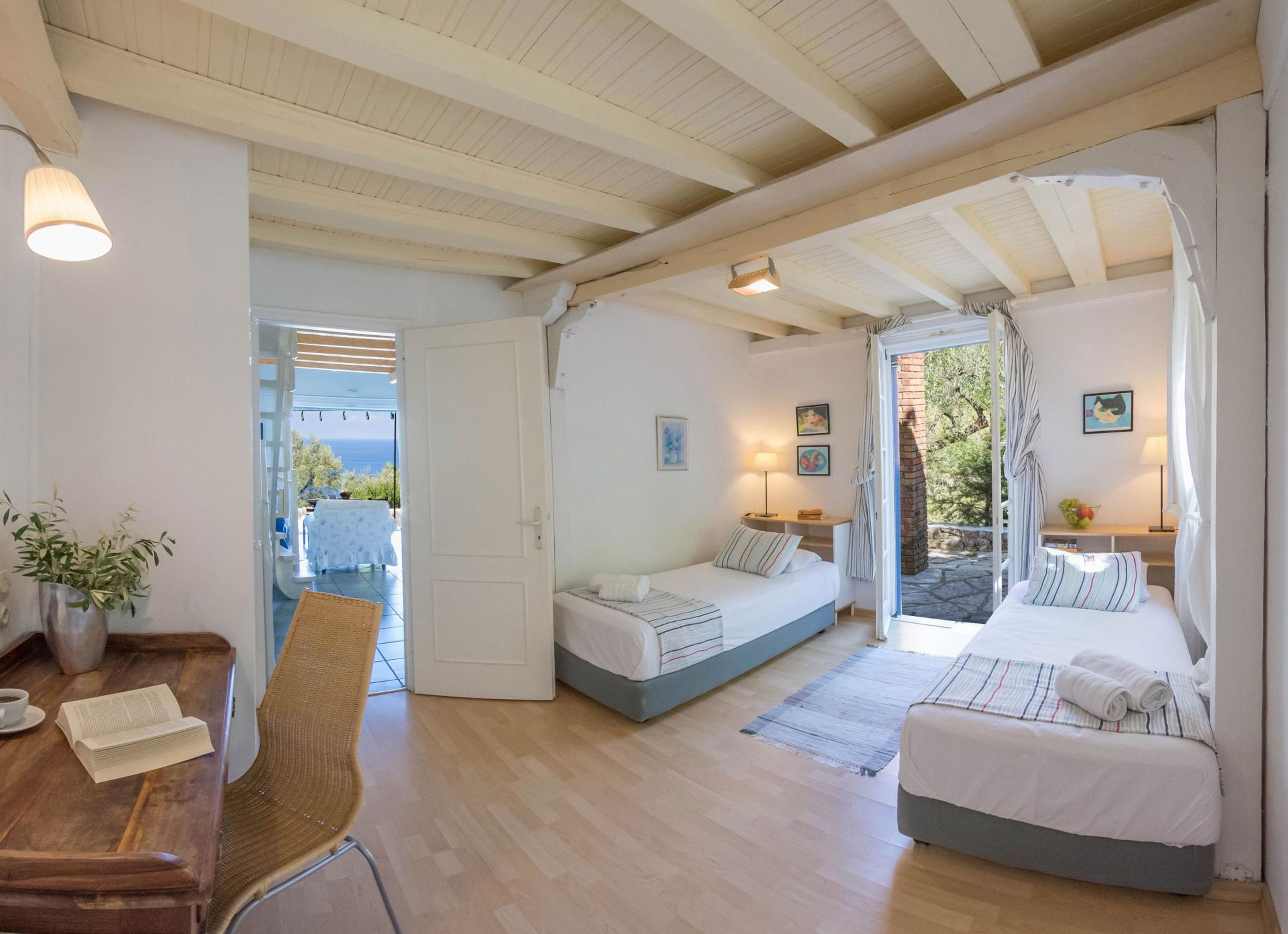 Una camera accogliente con due letti, una scrivania in legno, una sedia e vista sul mare.