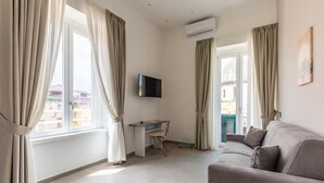 Una sala moderna con sofá, escritorio y televisor.