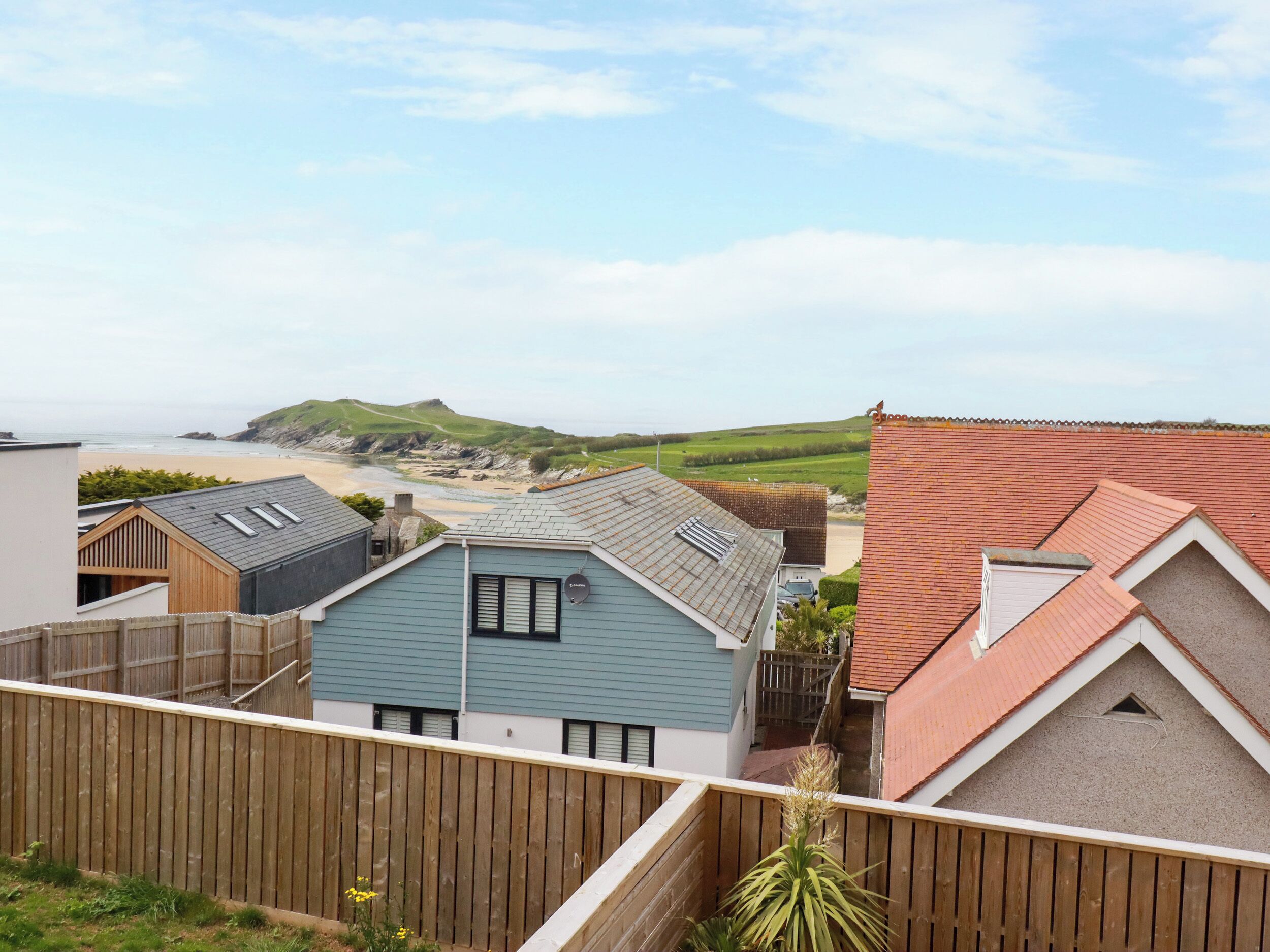 Zona residencial costeira com casas de telhados inclinados e vista para a praia.