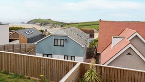 A coastal residential area with houses featuring pitched roofs and a view of the beach. - 11 Ebbtide (Newquay)