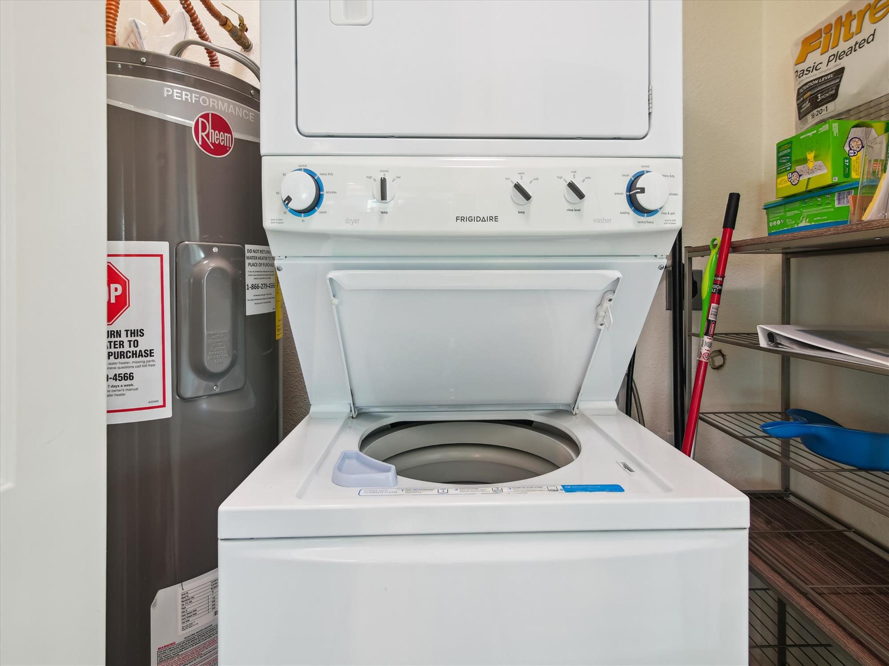 A front-loading washing machine with a control panel, a water heater, and a shelf with cleaning supplies.