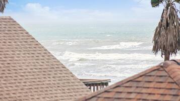 A beach view with a thatched roof structure in the foreground.
