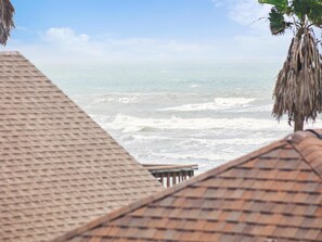 Vista de playa con una estructura de techo de paja al frente.