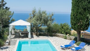 Une piscine dotée de chaises longues et d’un belvédère, offrant une vue panoramique sur la mer.
